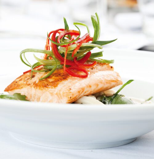 Artistically plated salmon dish close up of a salmon filet with vegetables in the restaurant